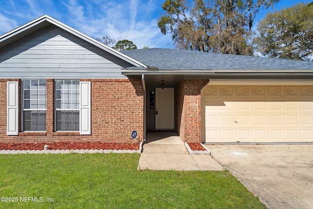 single story home featuring an attached garage, a shingled roof, a front lawn, concrete driveway, and brick siding