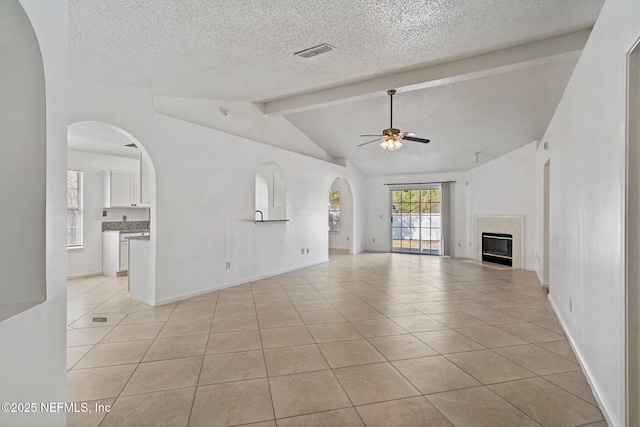 unfurnished living room with visible vents, vaulted ceiling with beams, ceiling fan, a premium fireplace, and light tile patterned flooring