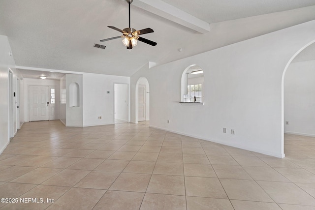 unfurnished living room featuring vaulted ceiling with beams, a ceiling fan, arched walkways, and light tile patterned floors