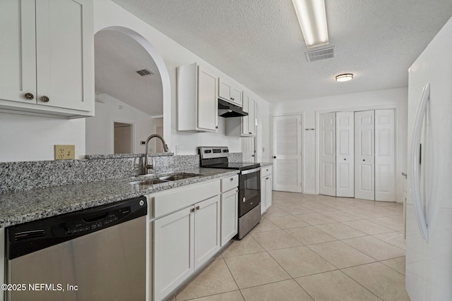 kitchen featuring under cabinet range hood, appliances with stainless steel finishes, light stone countertops, and a sink