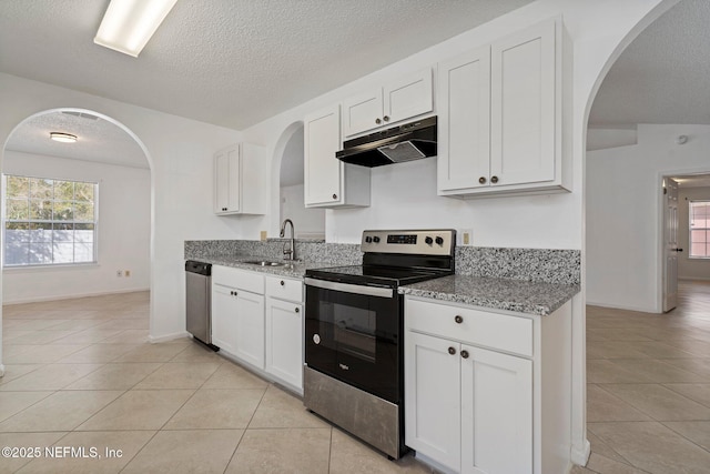 kitchen with under cabinet range hood, arched walkways, appliances with stainless steel finishes, and a sink