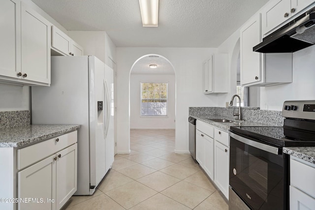 kitchen with arched walkways, a sink, stainless steel appliances, white cabinets, and under cabinet range hood