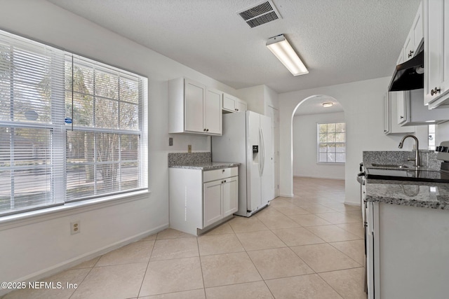 kitchen with light tile patterned floors, visible vents, electric range, arched walkways, and white refrigerator with ice dispenser