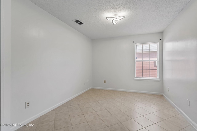 empty room with baseboards, visible vents, and a textured ceiling