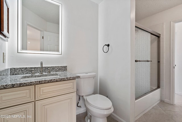 bathroom with vanity, enclosed tub / shower combo, a textured ceiling, tile patterned floors, and toilet