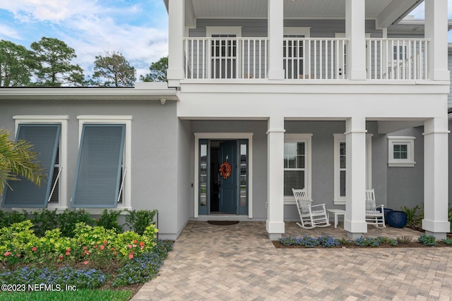 entrance to property featuring a porch and stucco siding