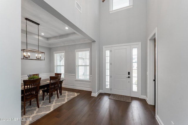 foyer entrance featuring visible vents, dark wood finished floors, a tray ceiling, recessed lighting, and an inviting chandelier