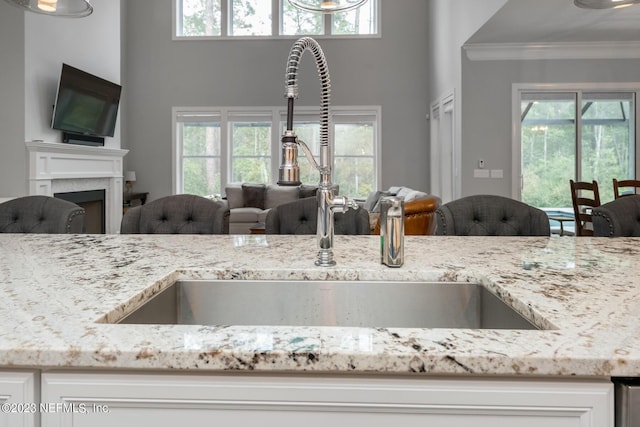 kitchen with open floor plan, a fireplace, light stone countertops, and a sink