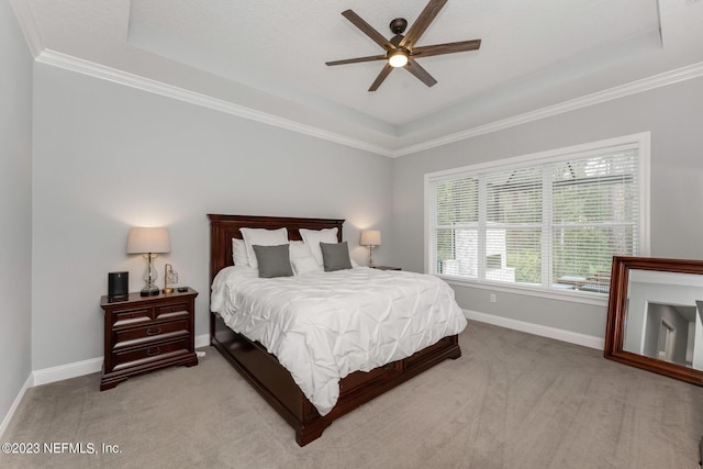 carpeted bedroom featuring baseboards, crown molding, and a tray ceiling