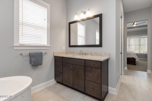 full bathroom with vanity, ensuite bathroom, baseboards, and a freestanding tub