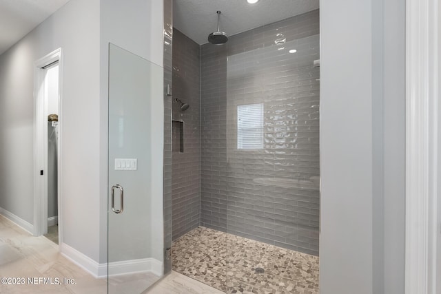 bathroom with baseboards and a shower stall