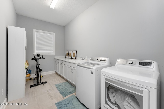 laundry room with a sink, baseboards, cabinet space, and washing machine and clothes dryer