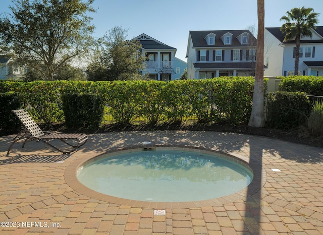 view of swimming pool featuring a community hot tub and fence