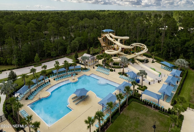 pool featuring a patio area, a view of trees, and a water slide