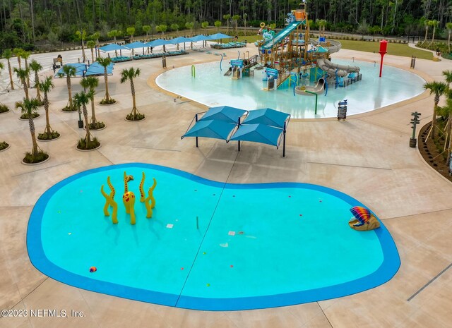 view of pool featuring a wooded view and playground community