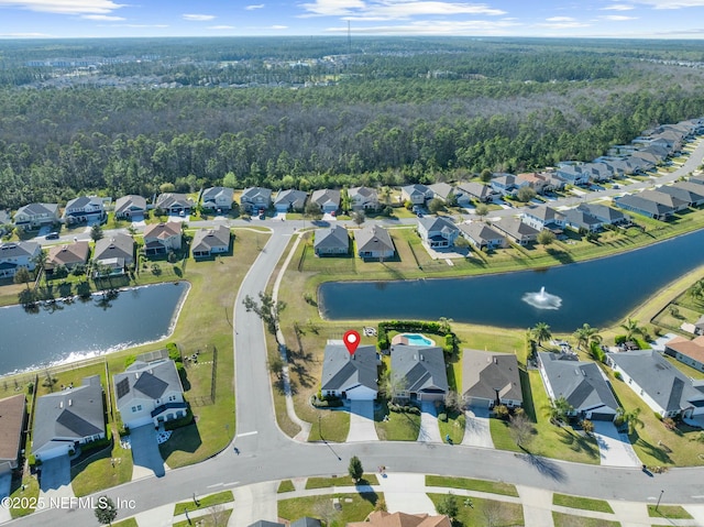 drone / aerial view featuring a residential view, a forest view, and a water view