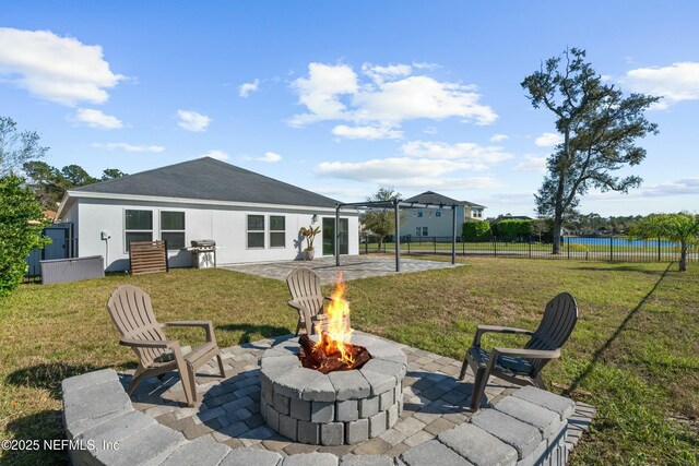 back of house with fence, an outdoor fire pit, stucco siding, a yard, and a patio area