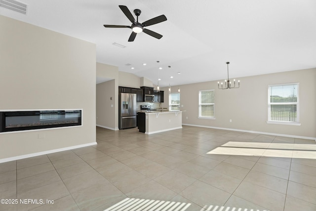 unfurnished living room with a glass covered fireplace, vaulted ceiling, light tile patterned floors, and visible vents