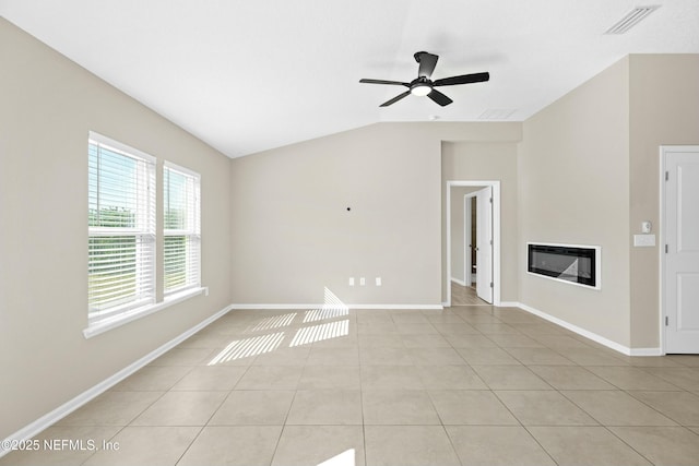 unfurnished living room with visible vents, baseboards, vaulted ceiling, light tile patterned flooring, and a glass covered fireplace