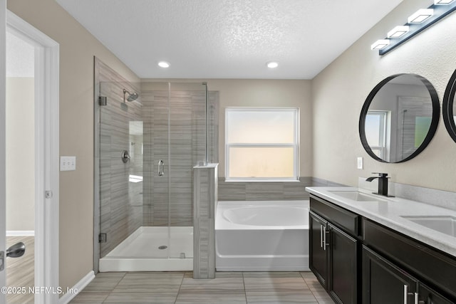 bathroom with a sink, a garden tub, a textured ceiling, and a stall shower