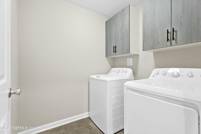 clothes washing area with washer and dryer, baseboards, cabinet space, and a textured ceiling