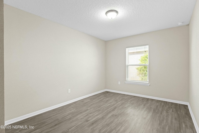 empty room featuring baseboards, a textured ceiling, and wood finished floors