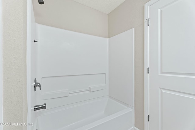 full bath with a textured ceiling and shower / washtub combination