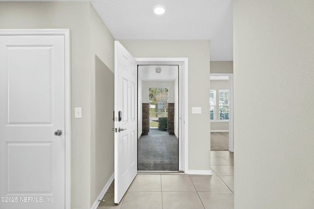 corridor with light tile patterned floors and baseboards