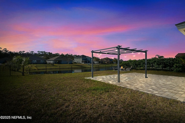 yard at dusk featuring a residential view, a pergola, a patio, and fence