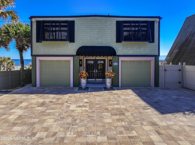 traditional-style house with fence, decorative driveway, a garage, and a gate