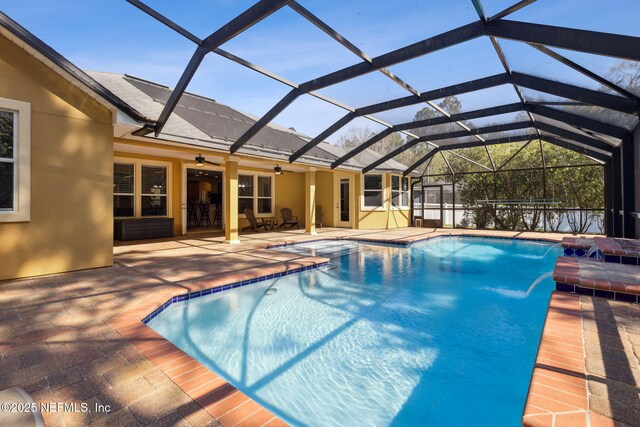 pool with a patio area, glass enclosure, and a ceiling fan