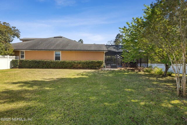 exterior space featuring a lanai, a yard, a fenced backyard, and stucco siding