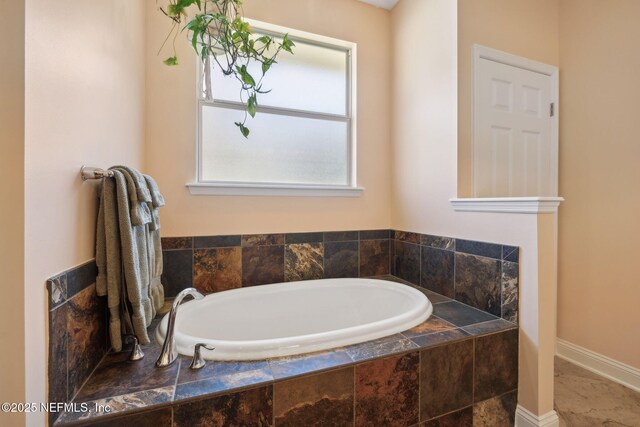 bathroom with a garden tub and baseboards