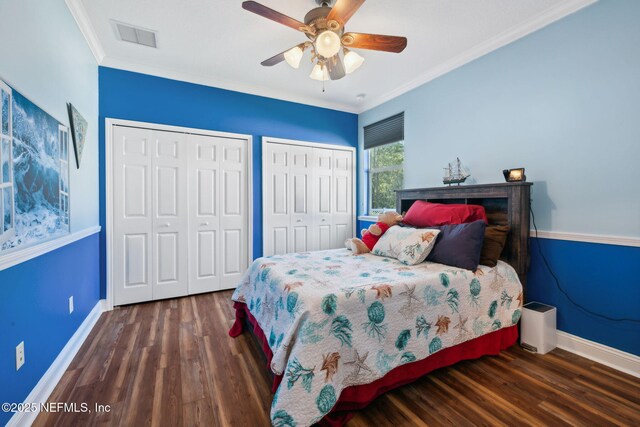 bedroom featuring crown molding, wood finished floors, multiple closets, and baseboards