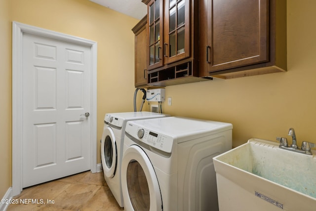 washroom with washing machine and clothes dryer, cabinet space, and a sink