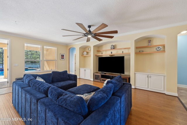 living area featuring built in shelves, a textured ceiling, and arched walkways