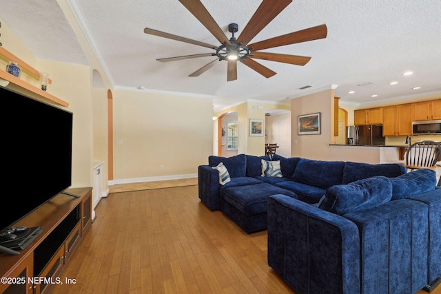 living room featuring arched walkways, light wood-style flooring, and a textured ceiling