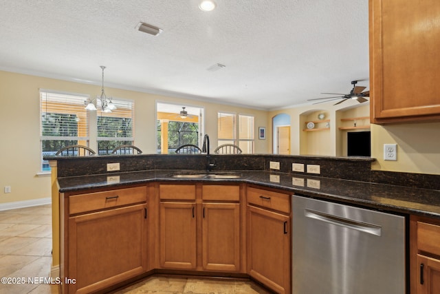 kitchen featuring stainless steel dishwasher, a textured ceiling, dark stone countertops, and a sink