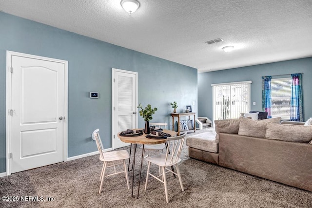 carpeted dining room featuring visible vents, a textured ceiling, and baseboards