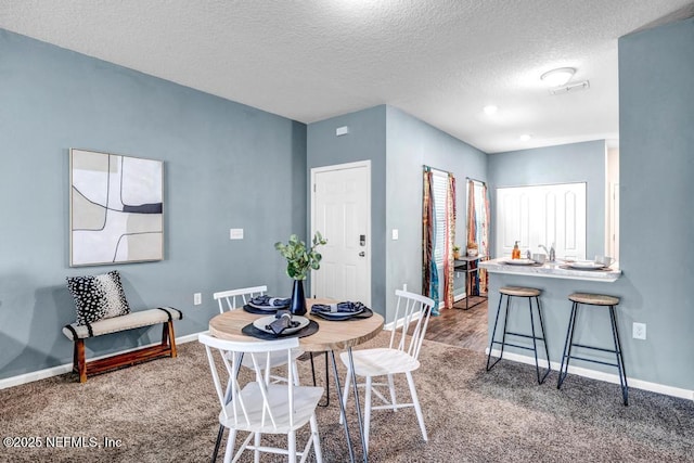 carpeted dining room featuring visible vents, baseboards, and a textured ceiling