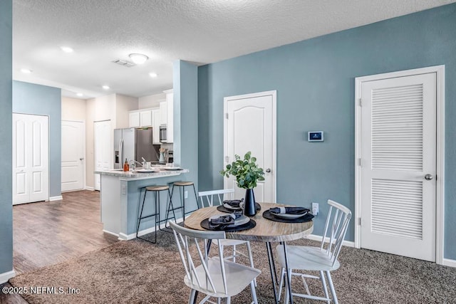 dining area featuring baseboards, dark colored carpet, and a textured ceiling