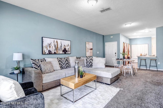 living room with baseboards, visible vents, carpet floors, and a textured ceiling