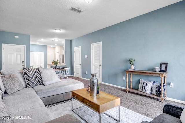 living area featuring carpet flooring, baseboards, visible vents, and a textured ceiling