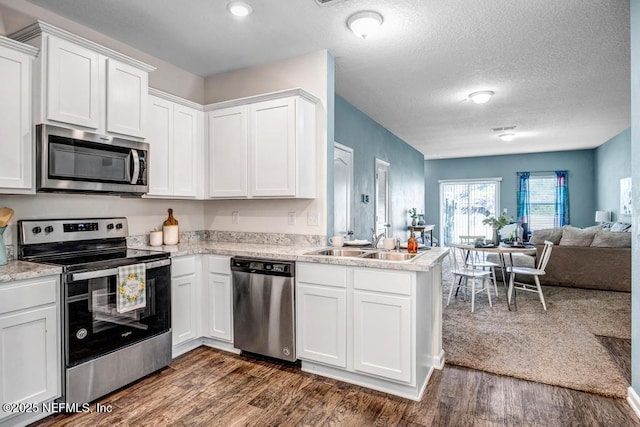 kitchen featuring open floor plan, white cabinets, appliances with stainless steel finishes, and dark wood-type flooring