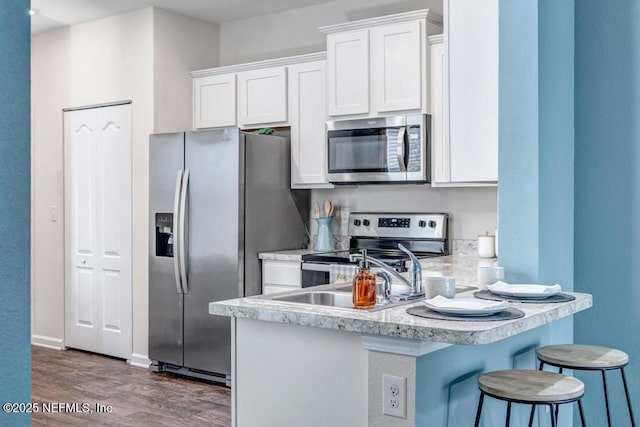 kitchen featuring a peninsula, appliances with stainless steel finishes, white cabinets, and light countertops