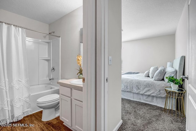 ensuite bathroom featuring toilet, vanity, wood finished floors, shower / bath combination with curtain, and a textured ceiling