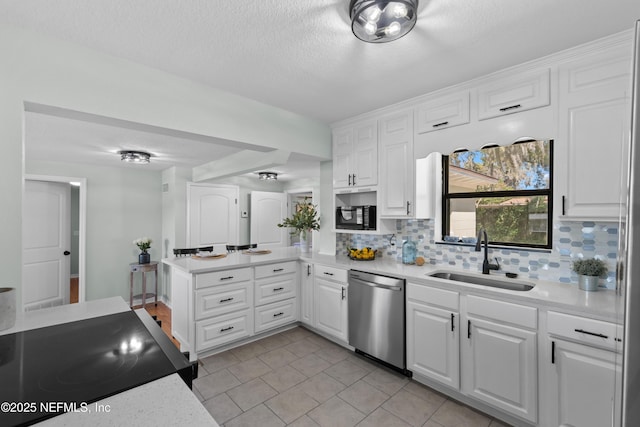 kitchen with light countertops, decorative backsplash, a peninsula, stainless steel dishwasher, and a sink