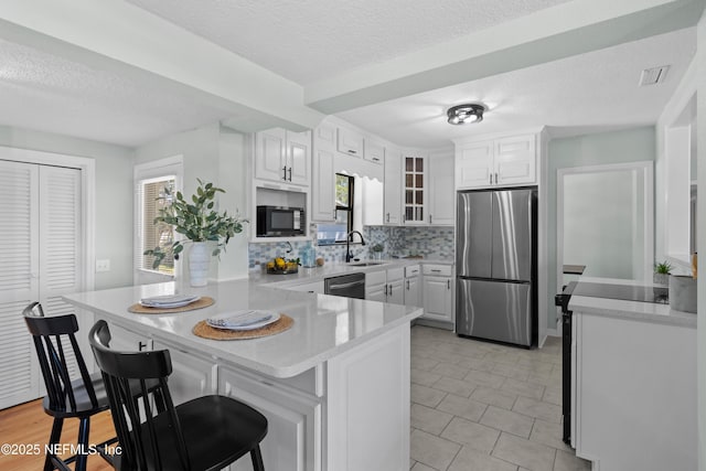 kitchen with a kitchen bar, a peninsula, light countertops, and stainless steel appliances