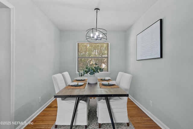 dining space featuring a chandelier, baseboards, and wood finished floors