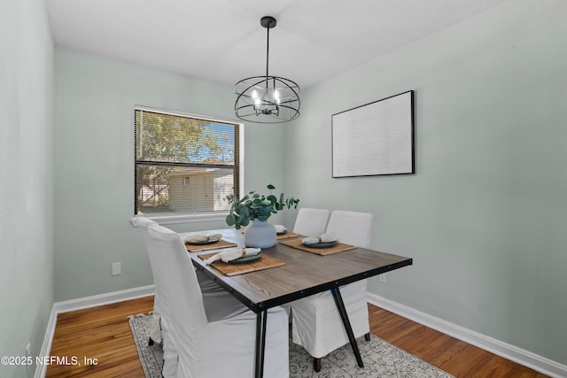 dining room featuring baseboards, a notable chandelier, and wood finished floors